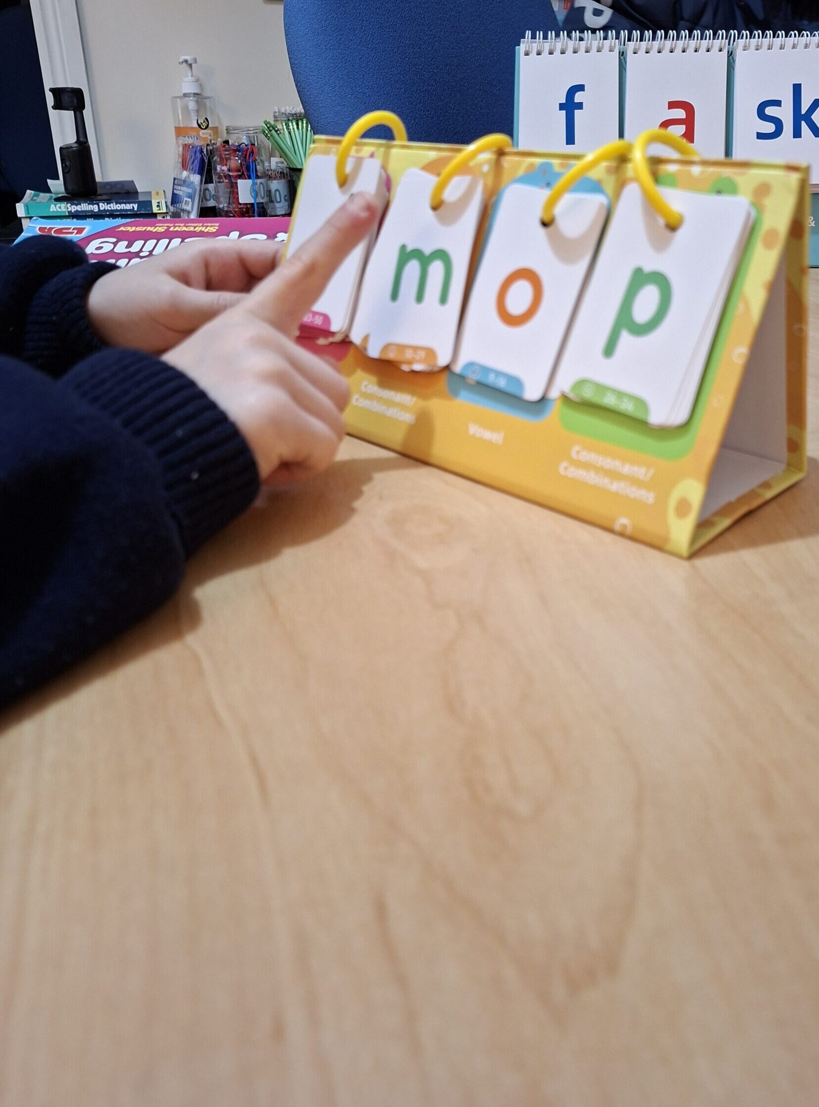 child spelling'mop' using a phonics flip chart