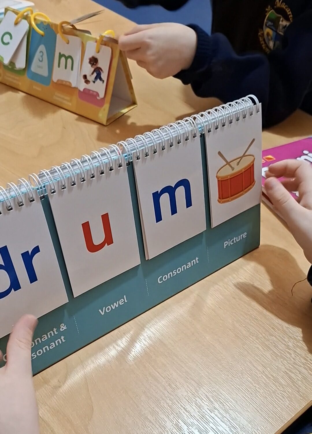 A child spelling 'drum' using a phonics flipbook